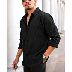 Man wearing a black textured shirt with rolled-up sleeves in an urban setting.